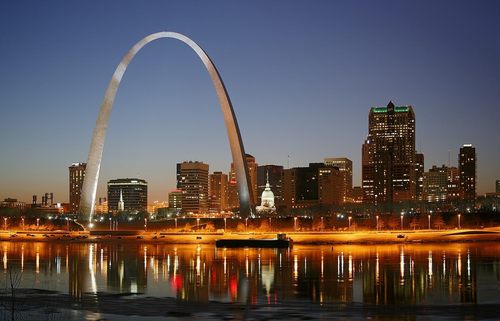 The Gateway Arch and downtown St. Louis skyline at night, reflected in the Mississippi River